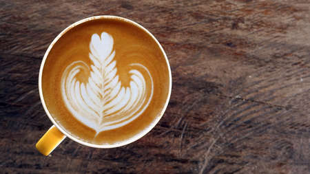 a cup of latte art coffee on wooden backgroundの写真素材