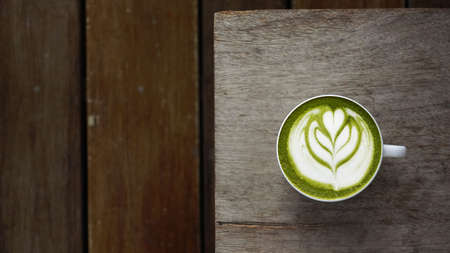 A cup of green tea matcha latte on wooden backgroundの写真素材