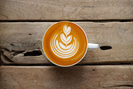 a cup of latte art coffee on wooden background