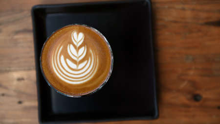 a cup of latte art coffee on wooden background