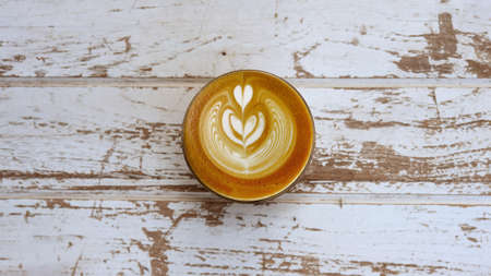 a cup of latte art coffee on wooden background