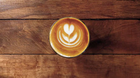 a cup of latte art coffee on wooden backgroundの写真素材