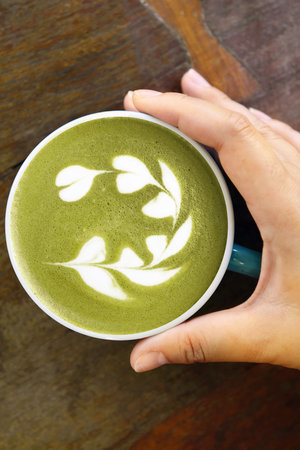 A cup of green tea matcha latte on wooden backgroundの写真素材