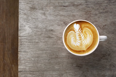 a cup of latte art coffee on wooden backgroundの写真素材