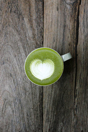 A cup of green tea matcha latte on wooden background