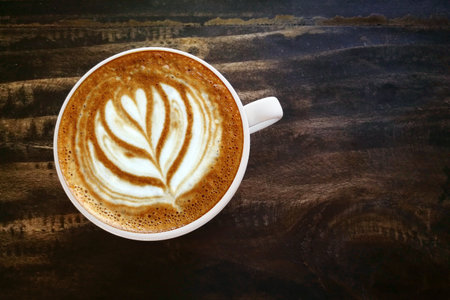 a cup of latte art coffee on wooden backgroundの写真素材
