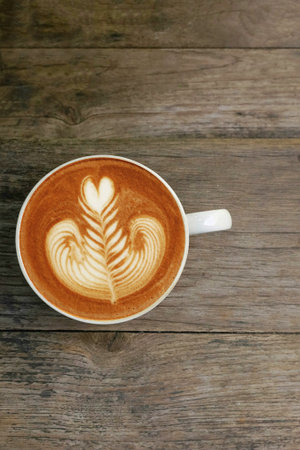 a cup of latte art coffee on wooden background