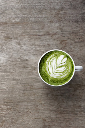 A cup of green tea matcha latte on wooden background
