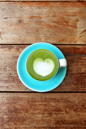 A cup of green tea matcha latte on wooden background
