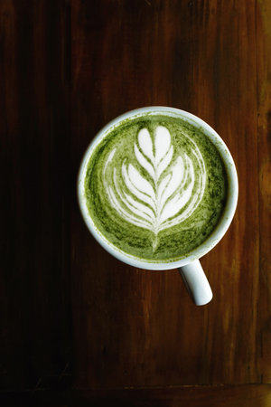 A cup of green tea matcha latte on wooden background