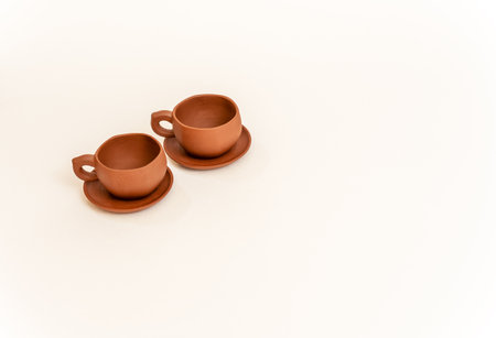 Two empty small brown clay cups with handles on saucersの写真素材