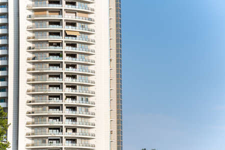 View of a high-rise building with balconies against the blue sky on a sunny dayの写真素材