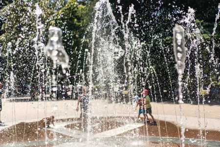 View of the foaming water jets and the spray of the city fountain up on a hot summer sunny day. An abstraction. The background is blurredの写真素材