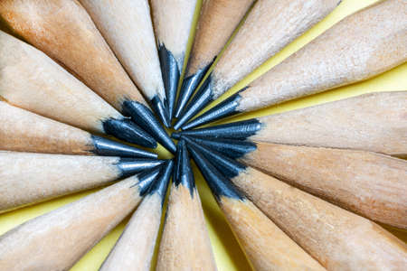 Top view of simple pencils lying in a circle, touching the pencils in the center on a yellow...
