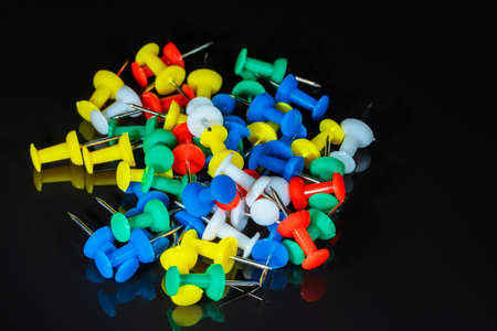 Top view of a bunch of colored stationery buttons on a black background. Large. Free space for copying, design or textの写真素材
