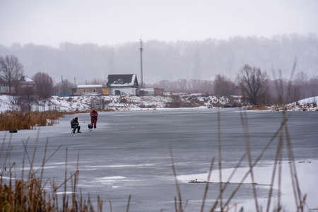 Fishermen in winter on a narrow river