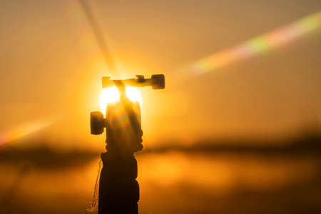Beautiful view of the silhouette of the tripod head, in the rays of the rising, morning, yellow sunの写真素材