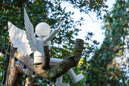 View of the city white lantern lighting angel with wings sitting on a tree branch in a recreation parkの写真素材