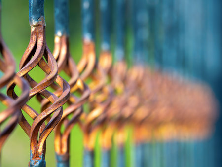A close-up view of a figured decorative element of yellow metal rusted fence. The background is...