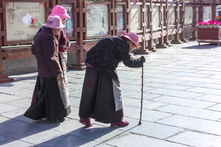 Three senior old women walking in everyday clothes on Barkhor Square in Lhasa, Tibet on a sunny day in Septemberの写真素材