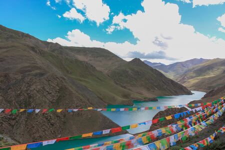 Mountain holy lake in Tibet with prayer flags- view from the highway on the way from Lhasa to Kailash, Tibet, Asiaの写真素材