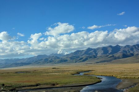 First view on Kailash Mountain rising from Barkha plain from the road from the distance with fields in front with riverの写真素材