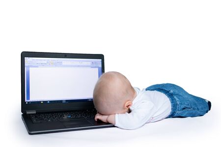 Baby boy lying on the floor with laptop looking with his head down, no face, tiredの写真素材