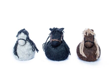 Three horses handmade of wool felt white, brown and black colors in a circle looking straight and standing in lineの写真素材