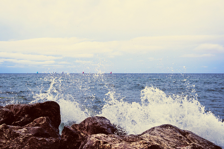 The spray of water froze in the air. Transparent white bubbles fly in all directions and fall. In the background, you can see many sails on the sea horizon.の写真素材