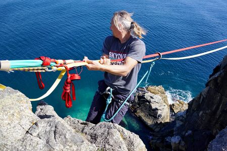 Slackliner holds on to the rope and prepares to go on the highline. Part of climbing equipment close-up. Bright colored ropes and knots. Russia, Vladivostokの写真素材