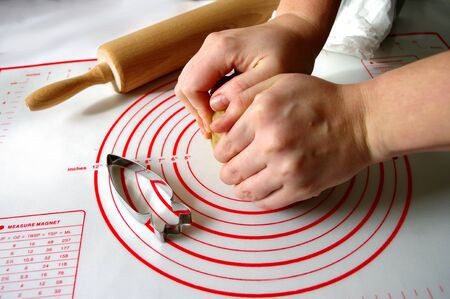 cooking and home concept, close up of female hands making cookies from fresh dough at home, carrot...
