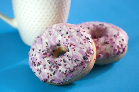 pink Glazed donuts with cup of coffee on blue background. Sweet food.の写真素材