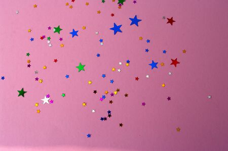 Colorful stars confetti on pink background. Carnival, party decoration. Celebration.