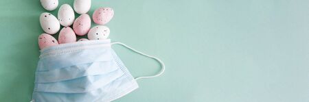 Easter banner quarantine concept. Protection mask , colorful eggs, health care. Blue green background, copy space.の写真素材