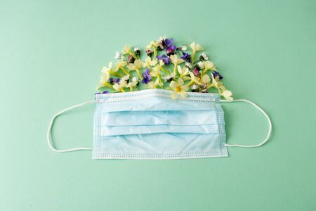 mask with yellow flowers on blue background. Spring allergy. Protective against coronavirus,...