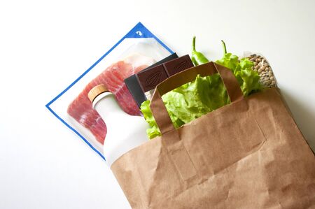 Paper bag with Food supplies, crisis food stock for quarantine isolation period.salad,oil, chocolate, bacon,lentils. Food delivery donation coronavirus. Copy space.の写真素材