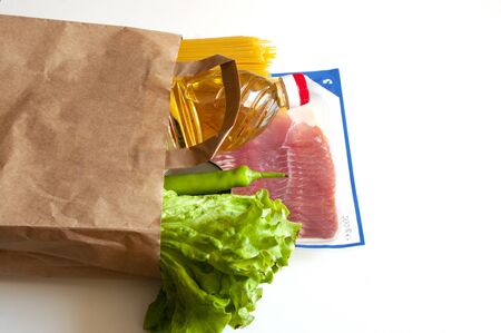 grocery in paper bag.Contactless delivery, donation essentials. Oil, pasta, salad, green chilli, canned foodの写真素材