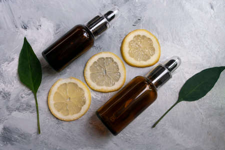 Natural cosmetics concept. Glass dropper bottles, lemons, green leaves. Copy space for text. Natural care.の写真素材
