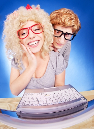 Funny guy is spying on girlfriend she is using laptop computer の写真素材