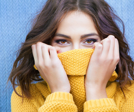 Beautiful natural young shy brunette woman with smiling eyes wearing knitted sweaterの写真素材