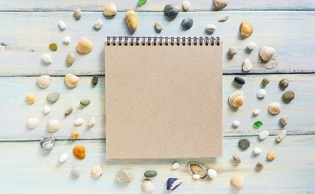 An open notepad and seashells on a rough wooden background. Concept of beach holidays. Flat lay, top view, copy space.の写真素材