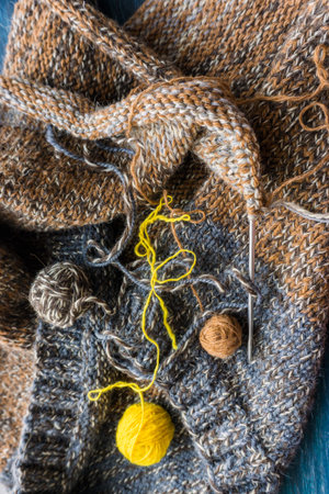 Knitting woolen scarf with knitting needles and ball of yarn.