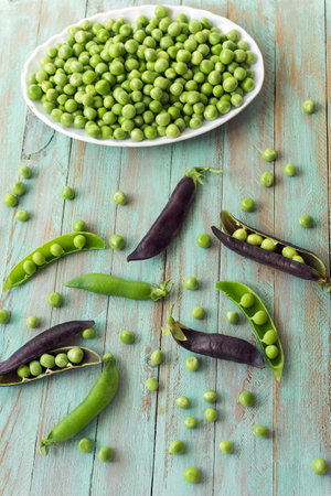 Green peas and pods on a blue wooden background. selective focus.の写真素材