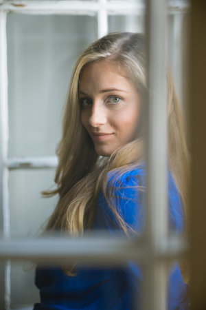 Portrait of young beautiful woman, taken through the window glass 