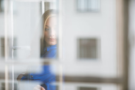Portrait of young beautiful woman, taken through the window glass with reflections