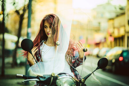 Young beautiful woman on motorcycle fixning her hairの写真素材