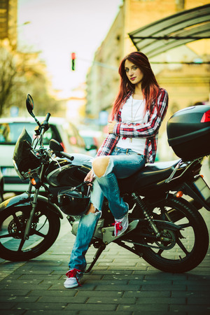 Young beautiful woman sitting on motorcycleの写真素材