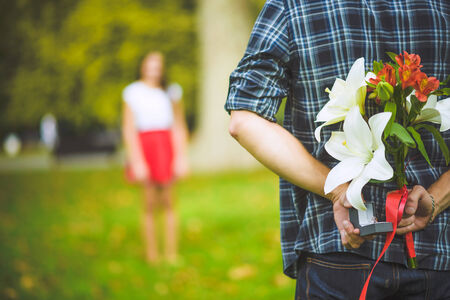 Man ready to give flowers to girlfriendの写真素材