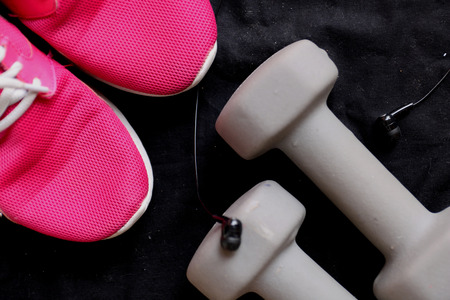 Sport equipment on black background. Sport wear, sport fashion, sport accessories. Sneakers, athletic shoes, dumbbells, headphones, earphones, bottle of water, jumping rope. Top view.の写真素材