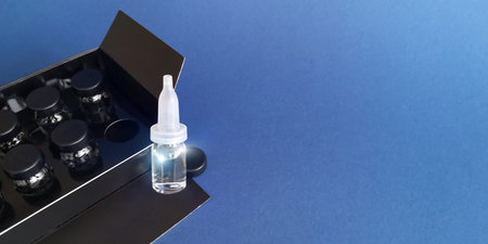 Glass bottle for cosmetics with dropper and vials in box on blue backgroundの写真素材
